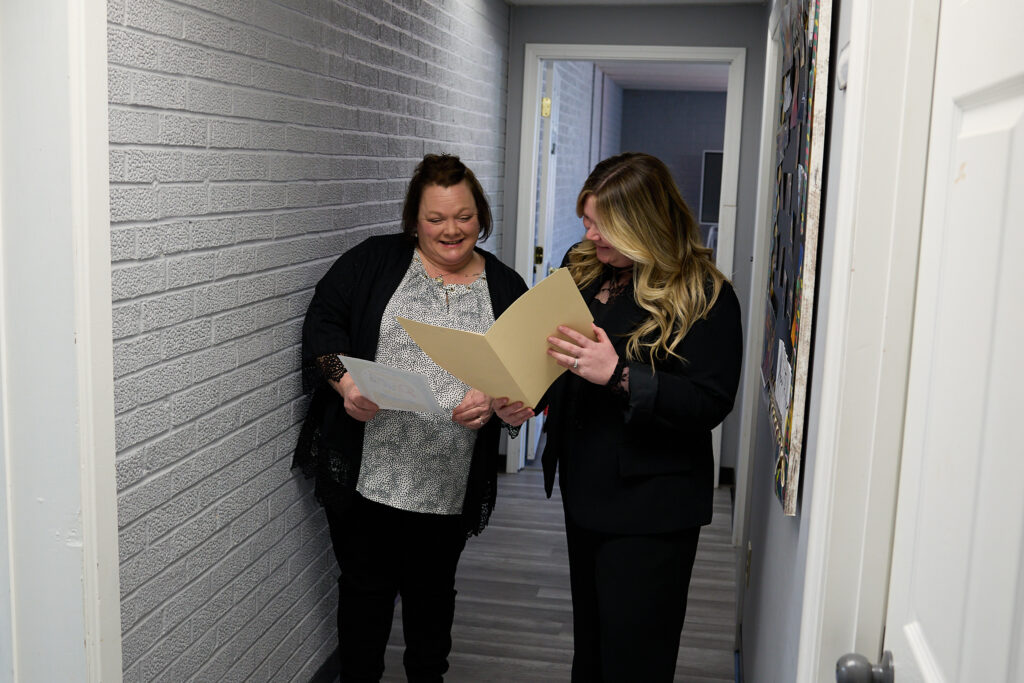 Health Plus Indiana team members consulting on case paperwork between meetings.